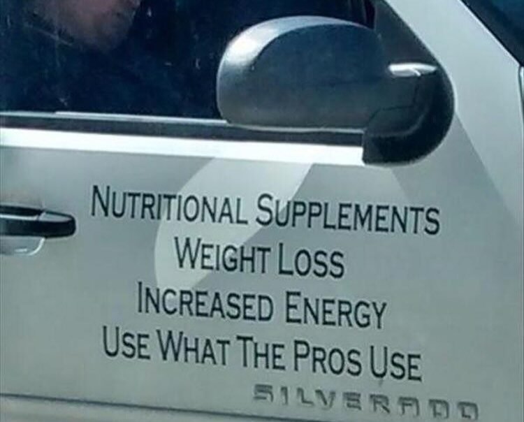 Guy sleeping in truck with sign promoting supplements to increase energy